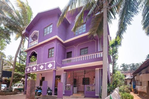 a purple house with palm trees in front of it at Ps Guest House Near Calangute Beach in Calangute
