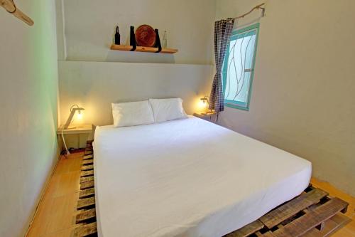 ein großes weißes Bett in einem Zimmer mit Fenster in der Unterkunft OYO 92825 Kamar Lombok in Kuripan