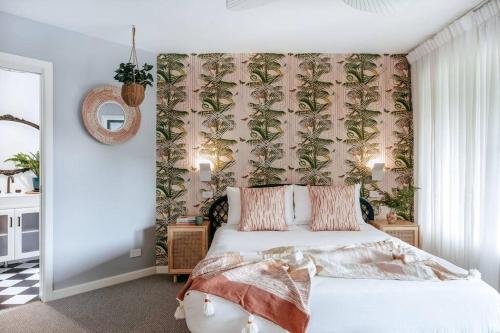 a bedroom with a bed with a tropical wallpaper at Jungle Cubby - by Coast Hosting in Terrigal