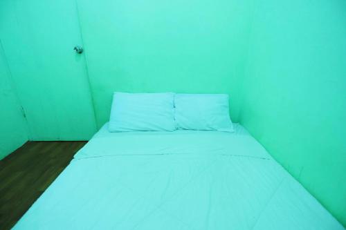 uma pequena cama num quarto com uma parede azul em SPOT ON 92843 Paris Syariah em Nagoya