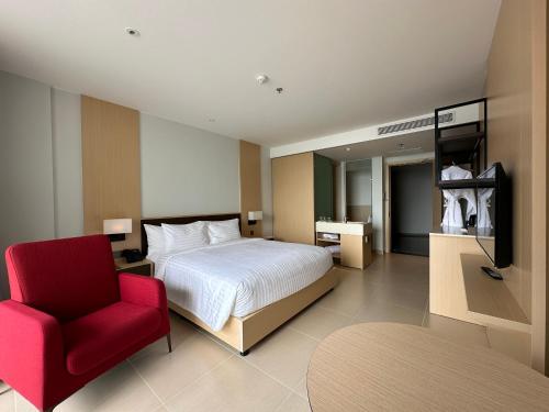 a bedroom with a bed and a red chair at The Arena Cam Ranh Resort all Luxury Service in Miếu Ông