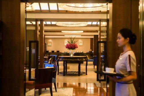 uma mulher a caminhar através de uma sala de jantar com uma mesa em The Ritz-Carlton Sanya, Yalong Bay em Sanya