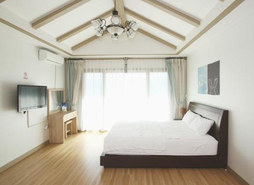 ein Schlafzimmer mit einem Bett und einem großen Fenster in der Unterkunft Jeju Soranghozen Pension in Seogwipo