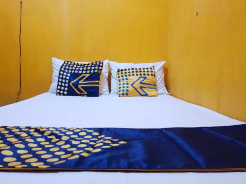 a bed with blue and white sheets and pillows at SPOT ON 92857 Kos Haji Jakfar Syariah in Banyuwangi