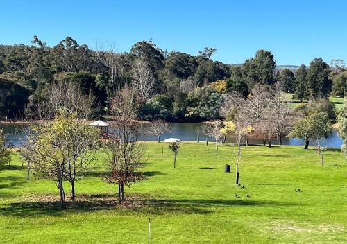 a field of grass with trees and a river at Caringal in the Valley Farm stay in Boyanup