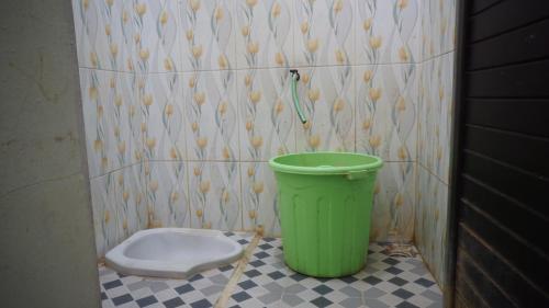 een groene vuilnisbak in een badkamer met een toilet bij SPOT ON 92860 Hunian 99 in Banyuwangi