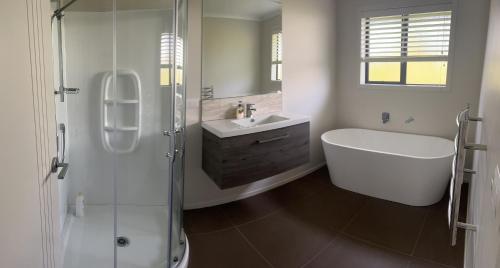 a bathroom with a shower and a tub and a sink at MataMata in Matamata