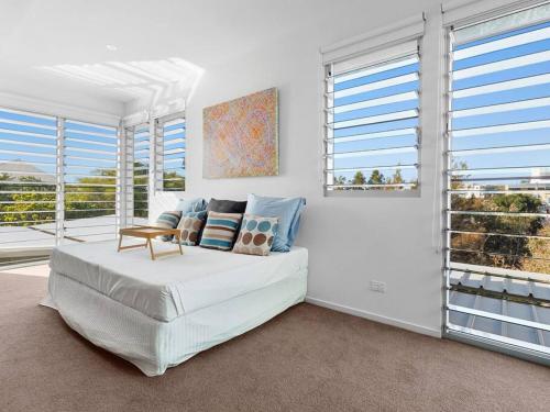 a white bedroom with a bed and windows at Friday Island Cabarita in Cabarita Beach