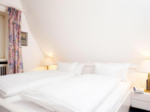 ein weißes Bett mit weißer Bettwäsche und Kissen in der Unterkunft Enenhoog Strandläufer  in Kampen