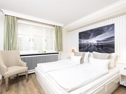 a white bedroom with a large bed and a chair at Kojenhof-2 in Kampen