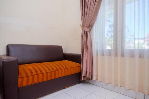 a couch with an orange blanket next to a window at RedDoorz Syariah near Alun Alun Wonosari in Yogyakarta