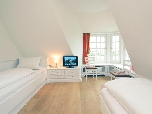 a white bedroom with two beds and a television at Broens-Fen in Kampen