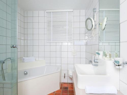a white bathroom with a tub and a sink at Kaeptn-Cook-4 in Kampen