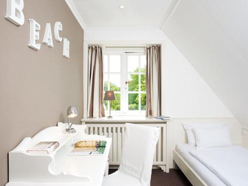 a white room with a desk and a bed and a window at Drosselhues-Sued in Kampen
