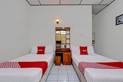 a room with two beds with red pillows at OYO 92885 Satriafi 2 Hotel in Yogyakarta