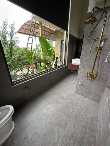 a bathroom with a shower and a toilet and a window at Ylang Farmstay in Buon Ma Thuot