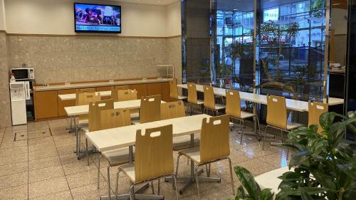 a dining room with tables and chairs and a tv at Toyoko Inn Kyoto Gojo-karasuma in Kyoto