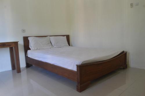 ein Bett mit einem Holzrahmen in einem Zimmer in der Unterkunft OYO 92880 Wisma Nusantara in Manado