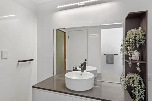 a white bathroom with a sink and a mirror at Humble Abode in Mollymook