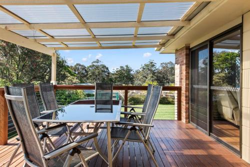 a patio with a table and chairs on a deck at Humble Abode in Mollymook