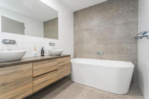 a bathroom with a white tub and two sinks at Harbour Sunrise in Ulladulla