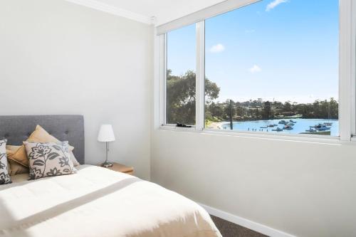 a bedroom with a bed and a large window at Harbour Sunrise in Ulladulla
