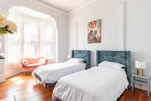 une chambre blanche avec deux lits et une chaise dans l'établissement Luxury Victorian House 10 mins to SF, Rose Garden & 3 Private Parking, à Oakland