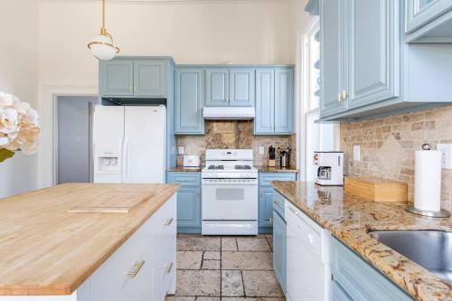 a kitchen with blue cabinets and a white refrigerator at Luxury Victorian House 10 mins to SF, Rose Garden & 3 Private Parking in Oakland
