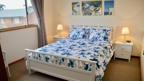 a bedroom with a white bed with blue flowers on it at Lighthouse Palms in Ulladulla