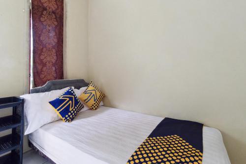 Un dormitorio con una cama con almohadas. en SPOT ON 92832 Al Mahira Syariah, en Majalengka
