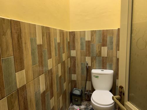 baño con aseo y pared de madera en OYO 92899 Penginapan Laota Syariah, en Luwuk