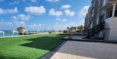a building with a green lawn next to the beach at מבנים בים 77 Suites at sea in Haifa