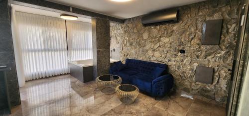 sala de estar con sofá azul y pared de piedra en מבנים בים 77 Suites at sea en Haifa