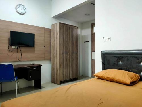 a bedroom with a bed and a desk and a tv at SPOT ON 92900 Kost 3 Kelor Syariah in Luwuk