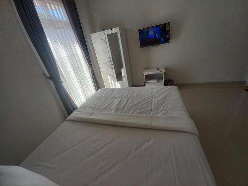 a white bed in a room with a window at OYO 92879 Imperial Inn in Cilacap