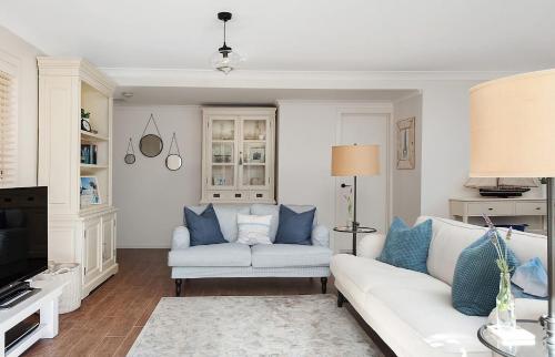 a living room with a white couch and blue pillows at No 1 Mollymook Beach in Mollymook