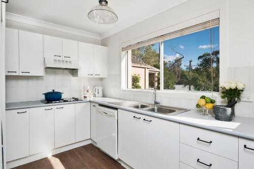 a white kitchen with a sink and a window at No 1 Mollymook Beach in Mollymook