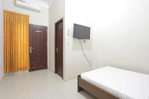 a bedroom with a bed and a tv on the wall at OYO 92865 Guest House Pandita in Sebawang