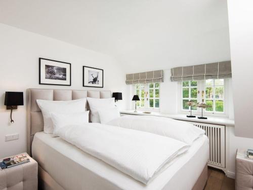 a white bedroom with a large bed with white sheets at Landhaus-Mare in Kampen