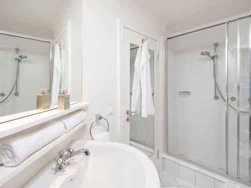 a white bathroom with a sink and a shower at Uhlenhof-E in Kampen