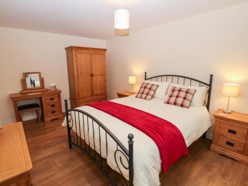 a bedroom with a large bed with a red blanket at The Lodge in Stockport