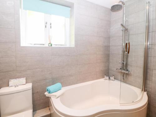 a bathroom with a tub and a toilet and a window at The Lodge in Stockport