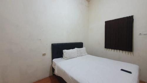 een wit bed met 2 kussens in een kamer bij RedDoorz Syariah At Demasto Homestay Jember in Jember