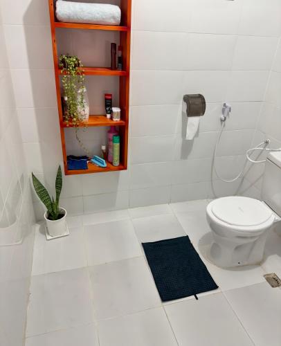 a white bathroom with a toilet and a shelf at Sally's home-near JNIA airport in Dar es Salaam
