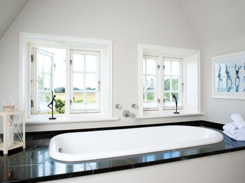 baño con bañera blanca grande y ventanas en Haus-zum-Leuchtturm en Kampen