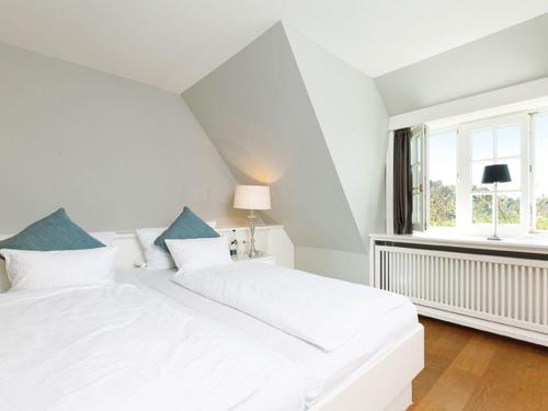 a white bedroom with a white bed and a window at Prahl-Hues-2 in Kampen