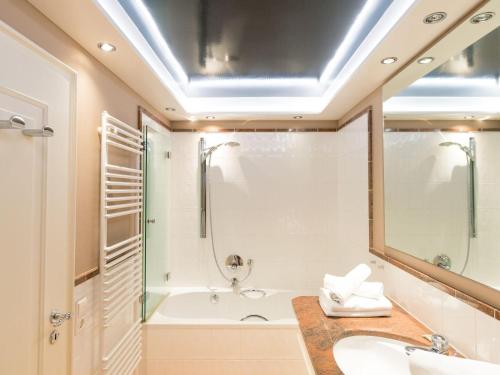 ein Badezimmer mit einer Badewanne, einem Waschbecken und einem Spiegel in der Unterkunft Prahl Hüs 3 in Kampen