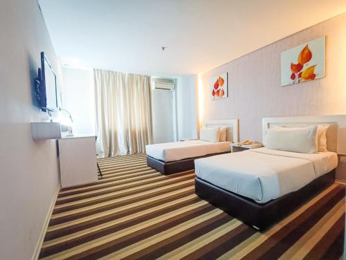 een hotelkamer met 2 bedden en een televisie bij First Residence Hotel by RVH in Cukai