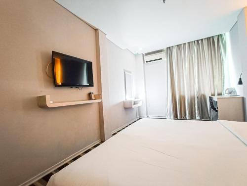 a hotel room with a bed and a flat screen tv at First Residence Hotel by RVH in Cukai