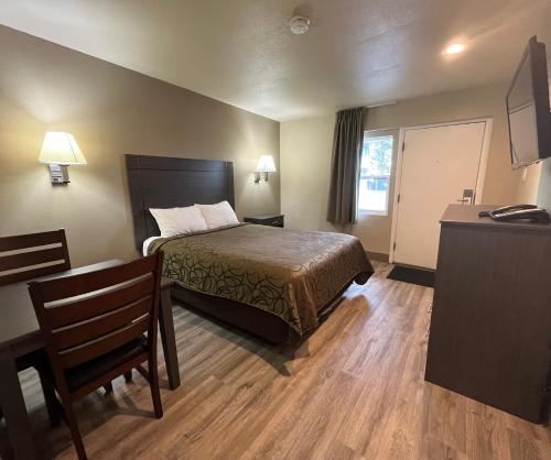 a hotel room with a bed and a table and chair at Mountain View Inn in Flagstaff